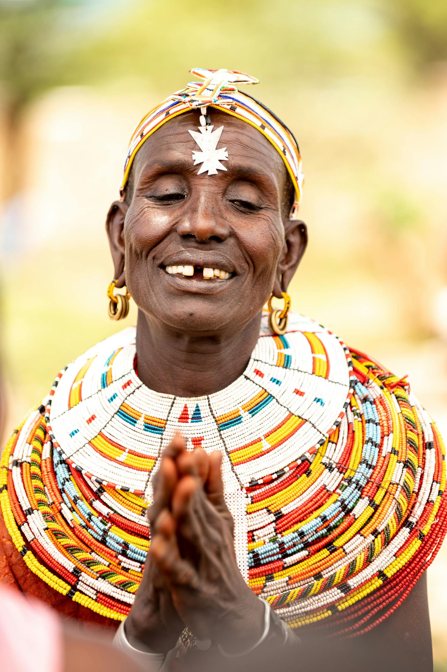 Elderly Samburu woman smiling, wearing colorful traditional beadwork in Kenya.