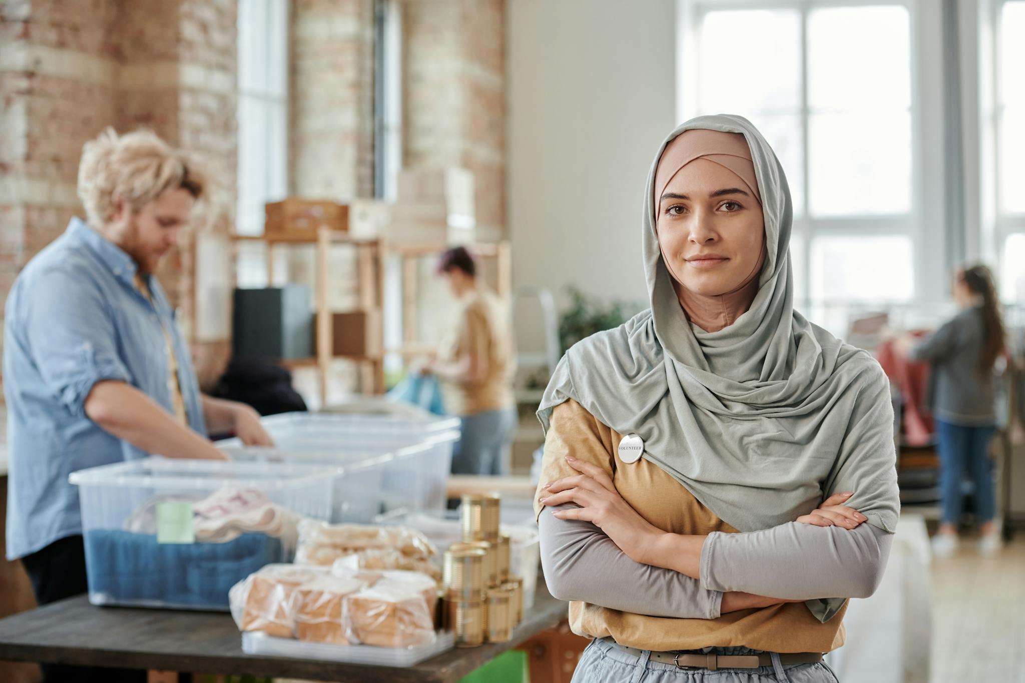 Woman in hijab poses confidently in a community donation center, symbolizing empowerment.